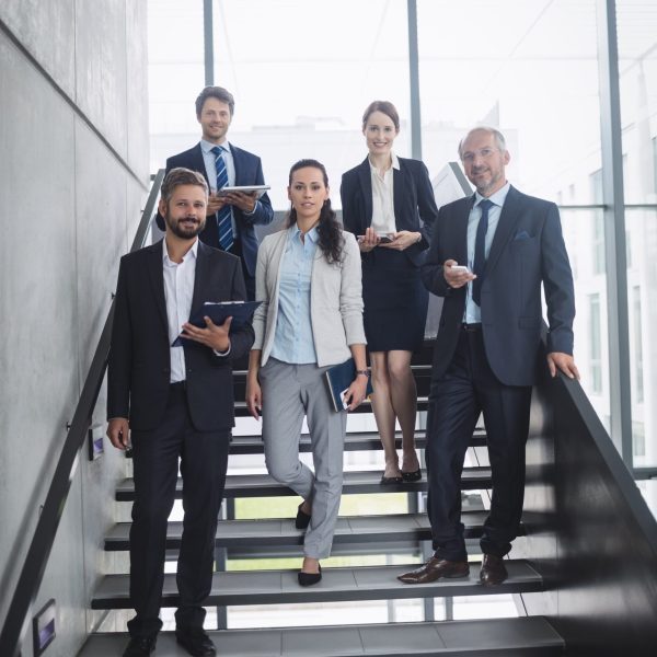 Portrait of confident businesspeople standing on staircase in office